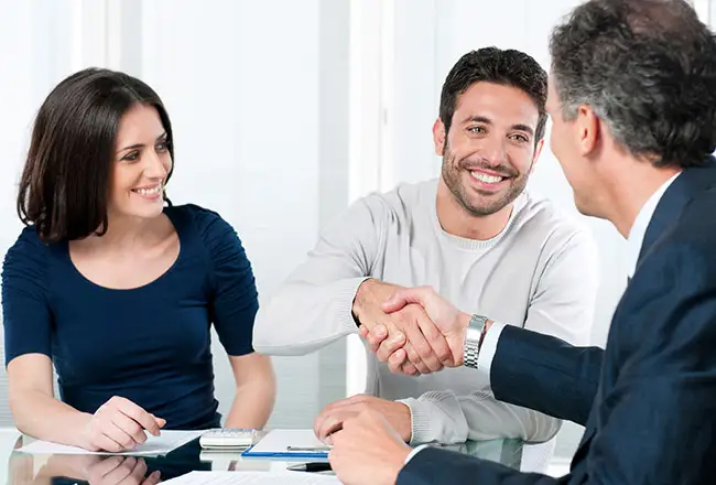 Couple shaking hands with man in suit while seated at table