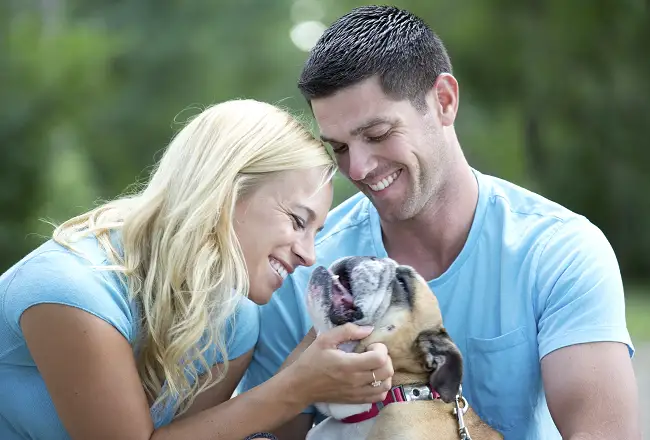 Woman and man petting and scratching pet dog