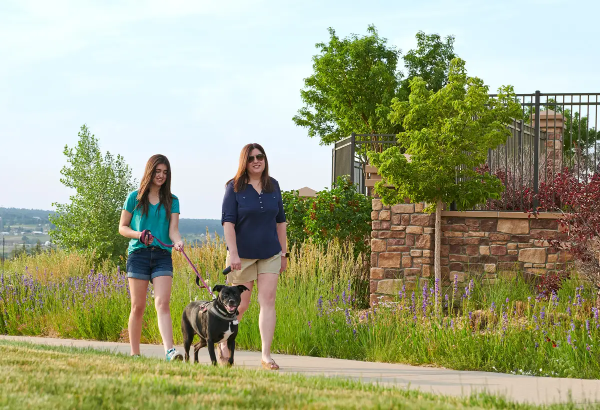 Mom walking next to daughter walking dog on the sidewalk