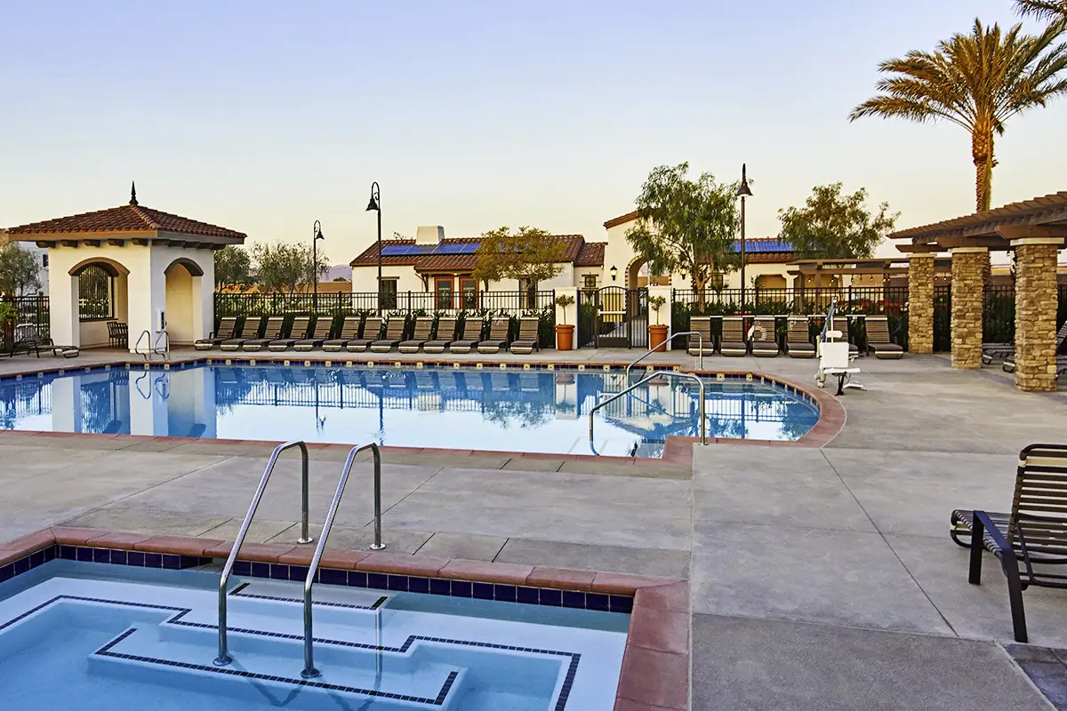 Fenced in community pool and hot tub surrounded by pool chairs