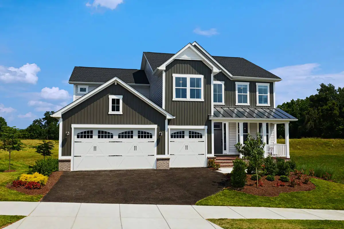 Two-story green home with small front porch and three-car garage