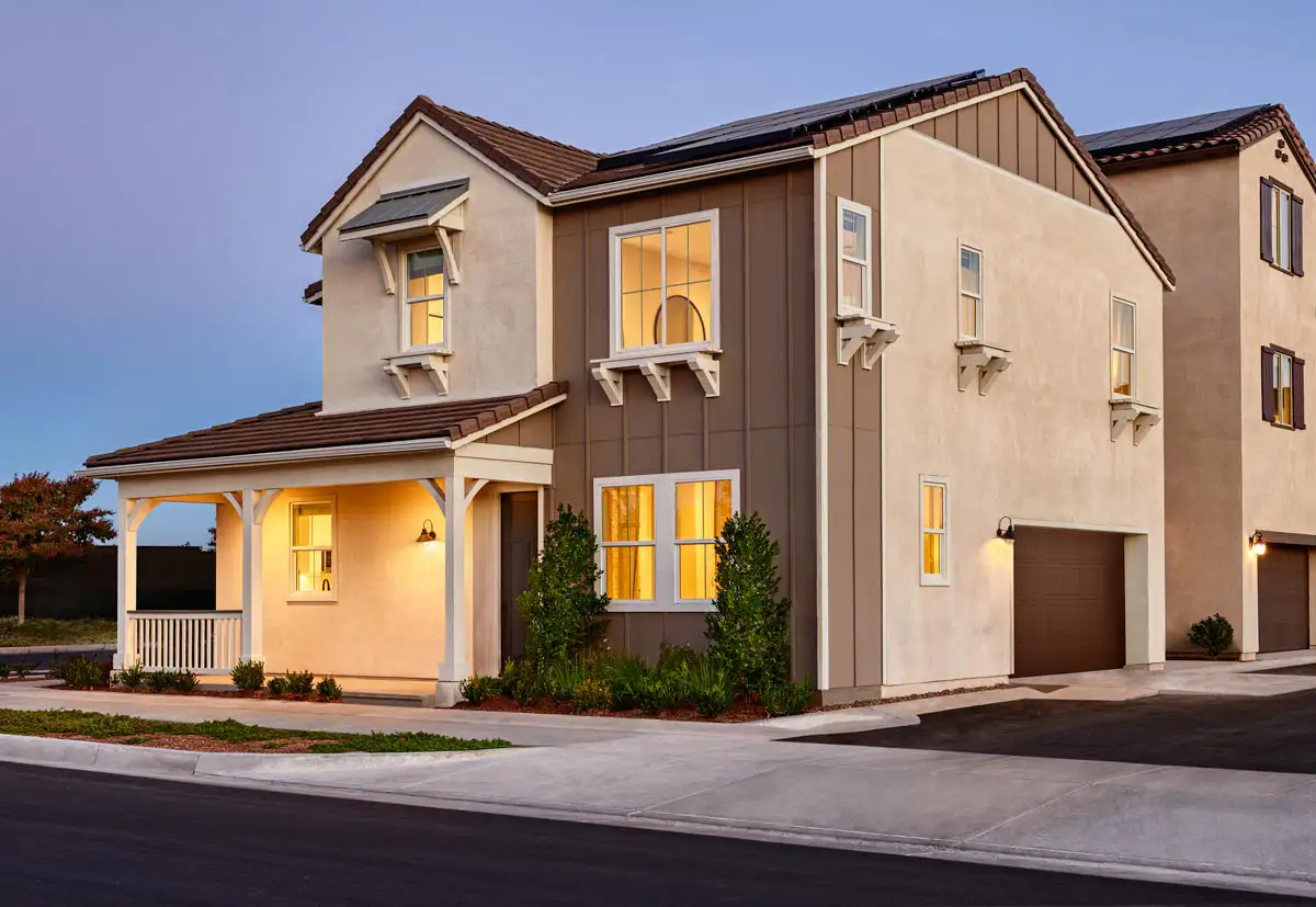 Two-story home on a street corner with lights on