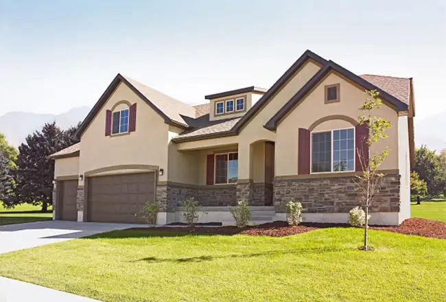 Exterior of home with three-care garage, stone accents, and wooden shutters