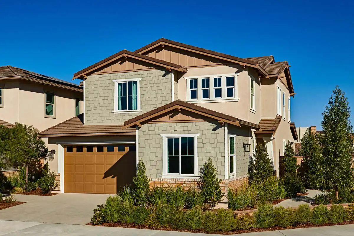 Exterior of two-story home with many windows and several bushes in front and beside it