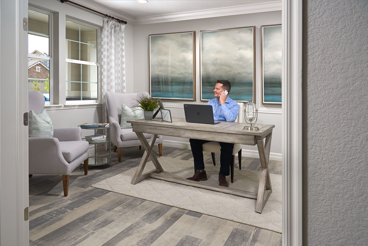 Man sitting at home office in front of laptop while talking on cell phone and looking out the window