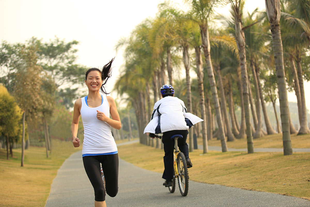 Woman smiling and jogging on path past biker going opposite direction