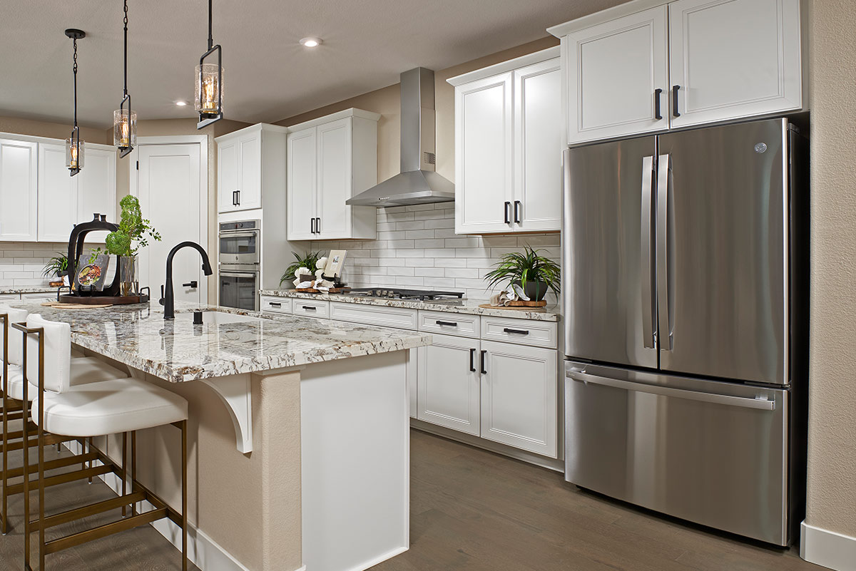 Kitchen with long island, large refrigerator, gas stove, double oven, and pantry door