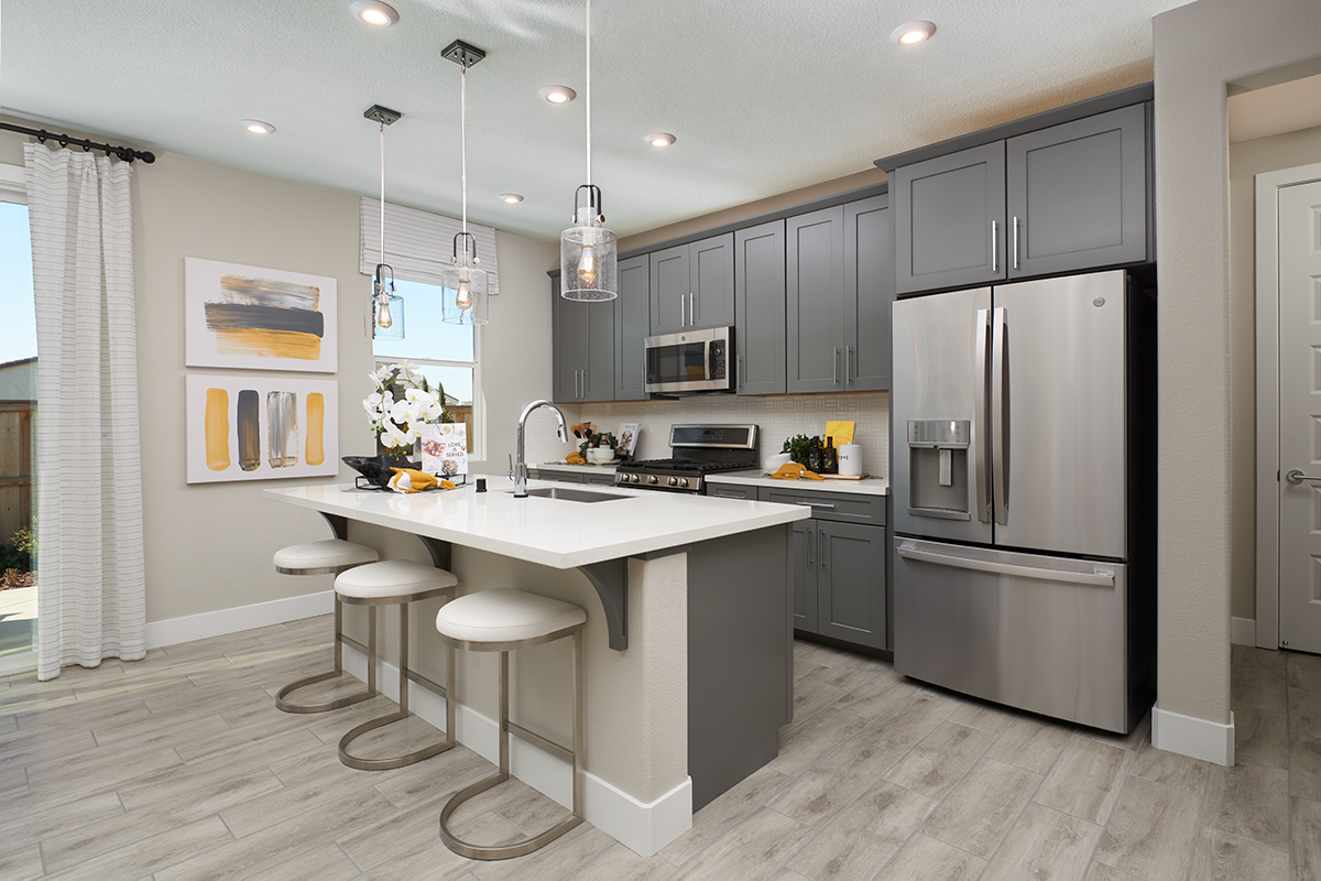 Kitchen with island in front of wall of cabinets, gas stove, and refrigerator