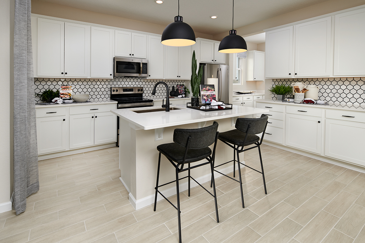 Kitchen with island with two chairs, cabinets on two walls and patterned backsplash