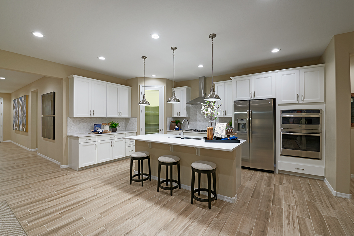 Light colored wood flooring in kitchen with white cabinets