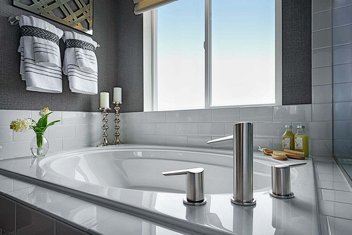 Bath tub by large window surrounded by tile