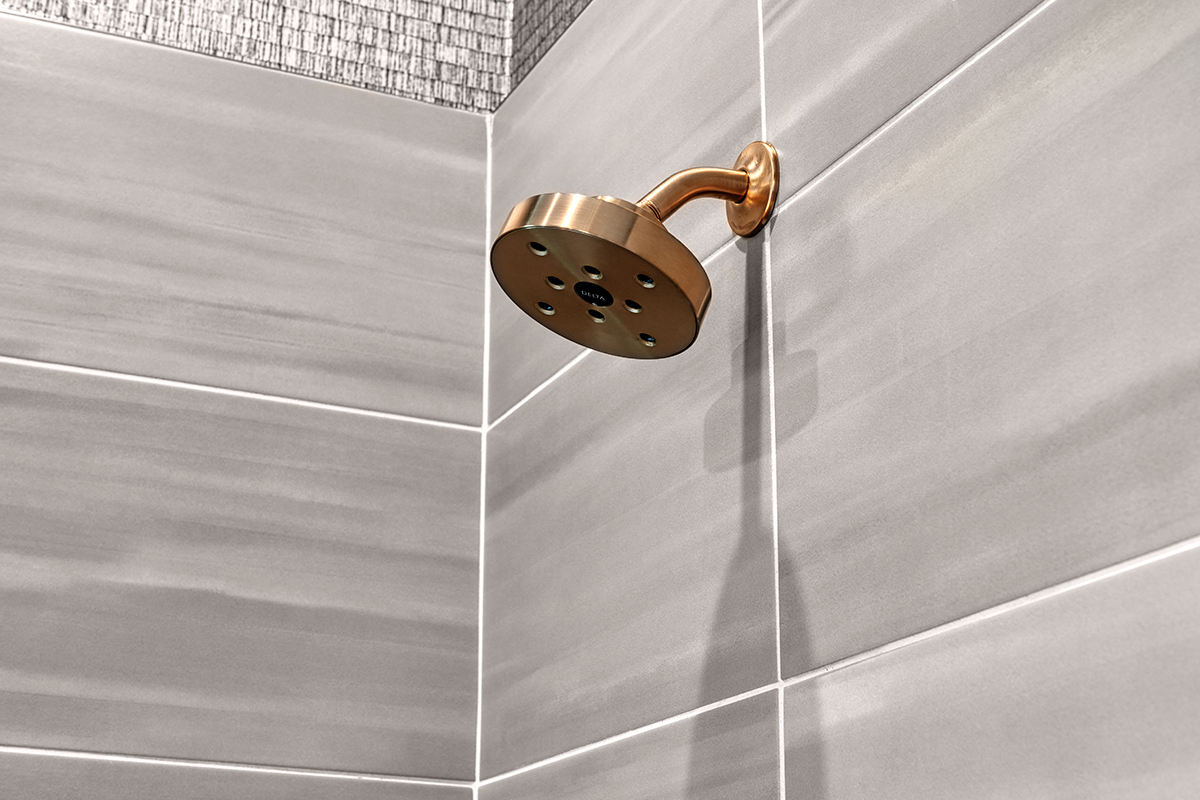 Gold showerhead on large gray square tiles